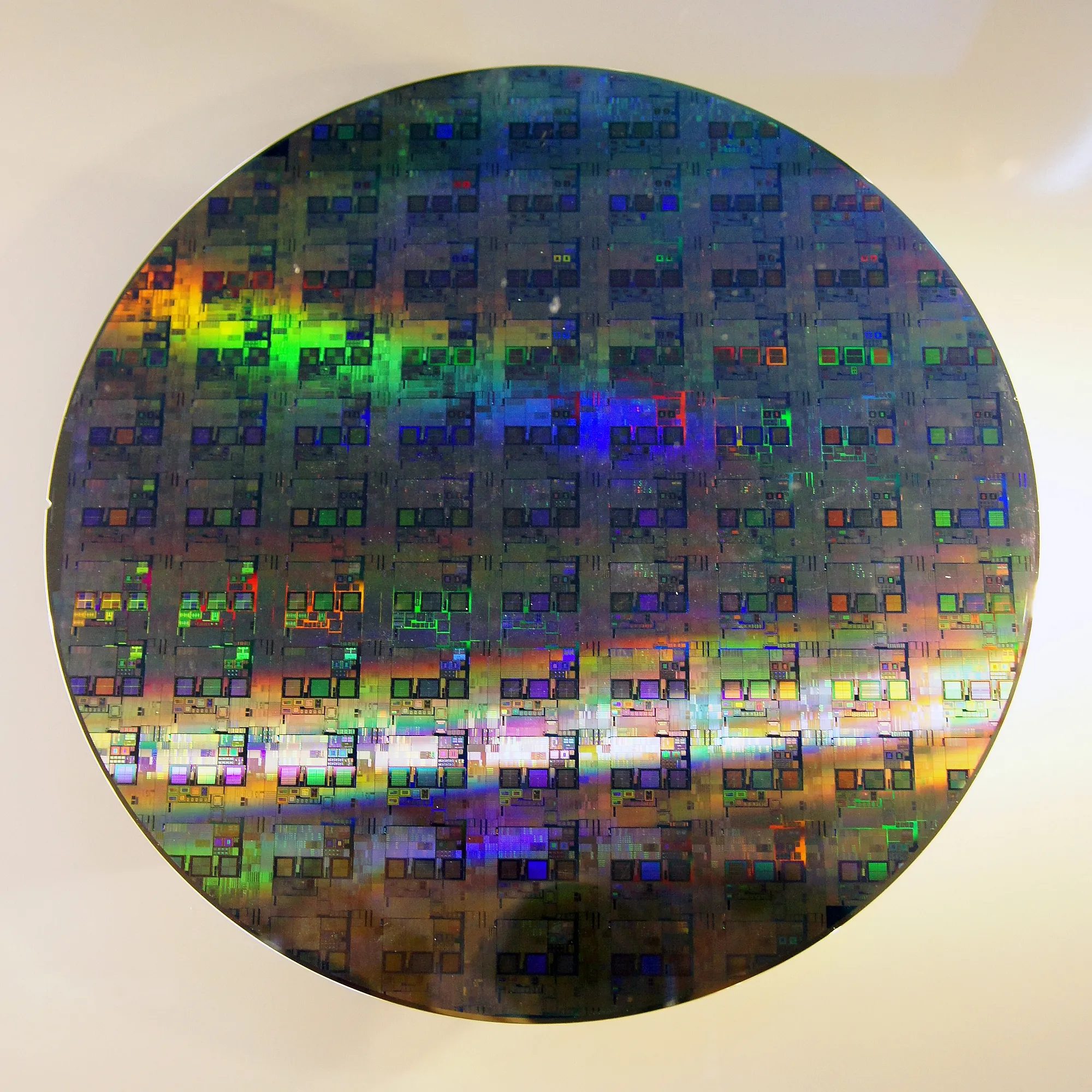 A polished 12-inch silicon wafer reflecting light, the raw material from which semiconductor memory chips are cut.