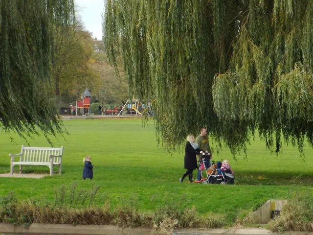 A young family walking together beside the river in St Nicholas Park, Warwick