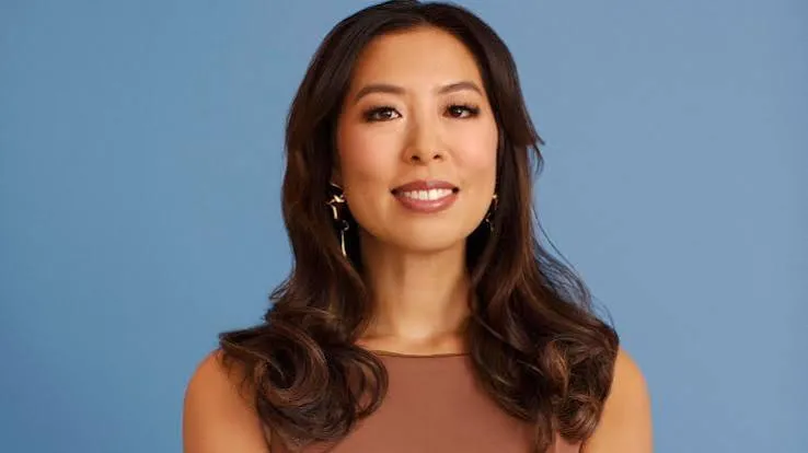 Vivien Wong, Smiling Asian woman, ice cream empire founder, against blue background.
